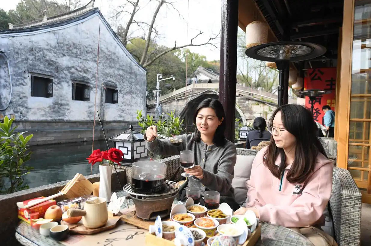 2024年3月13日,人们在仓桥直街的一家店铺围着炉火消费、休闲。